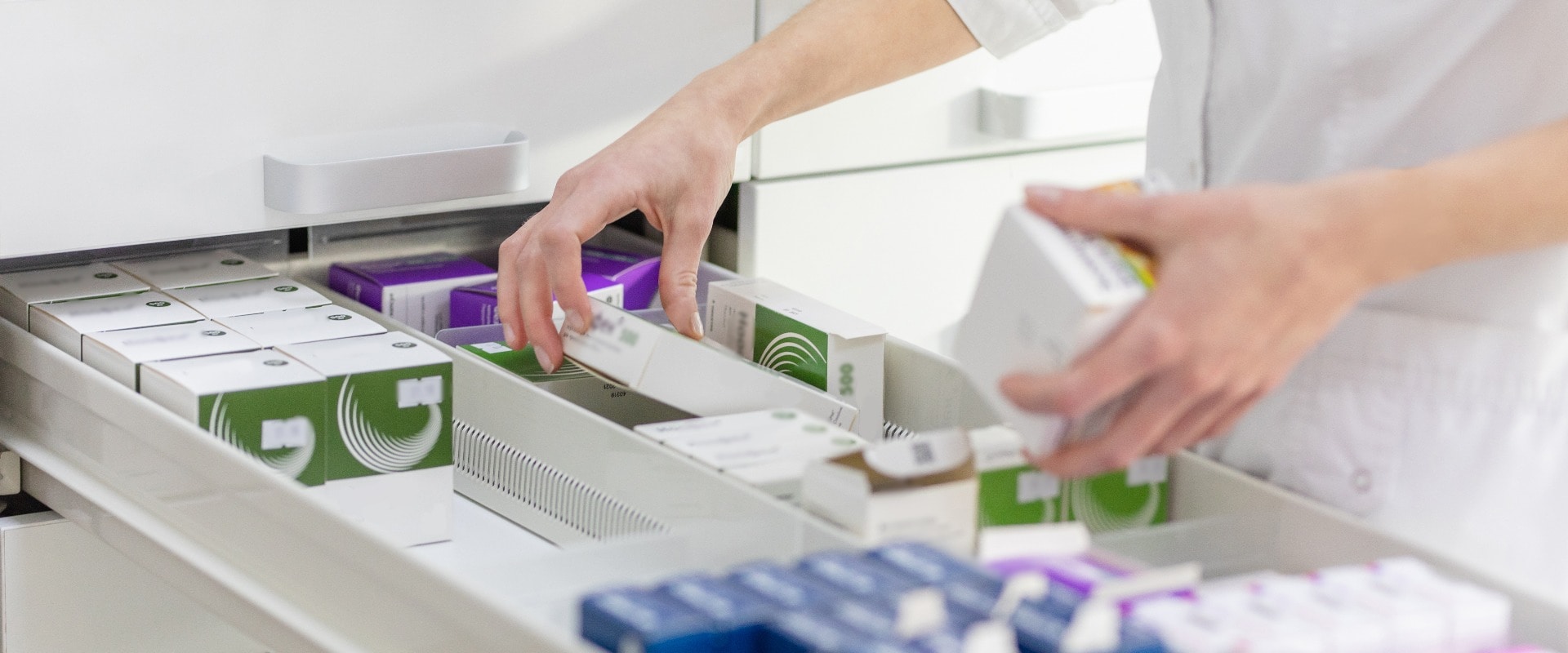 Apothekerin mit Medikamentenschachtel und Kapselpackung.